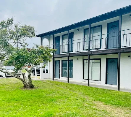 a motel with a balcony and a lawn in front of it at The Spanish Oaks