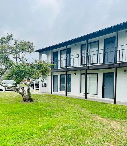 a motel with a balcony and a lawn in front of it at The Spanish Oaks